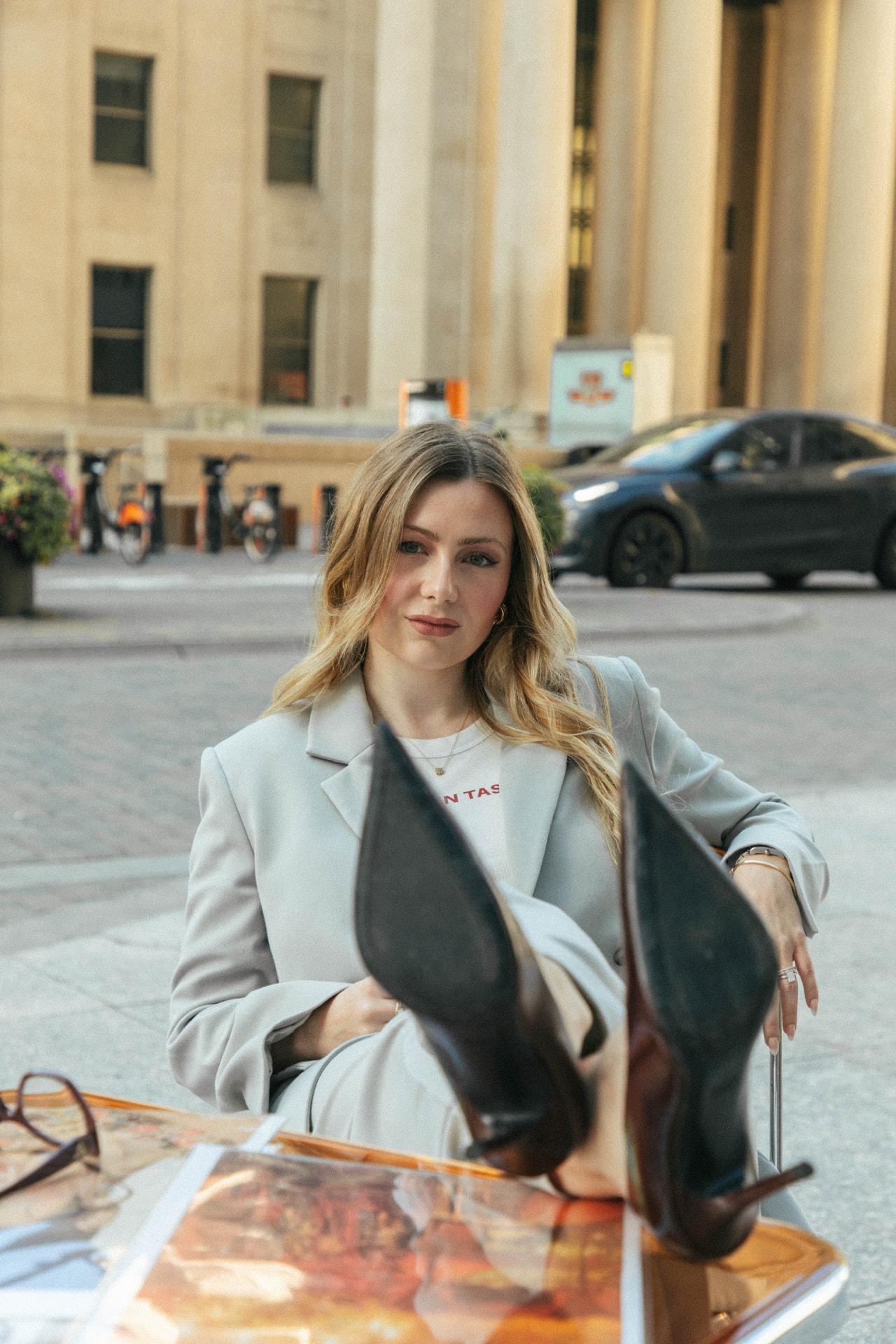 Sabina Bozzo seated outdoors in a pale tailored suit
